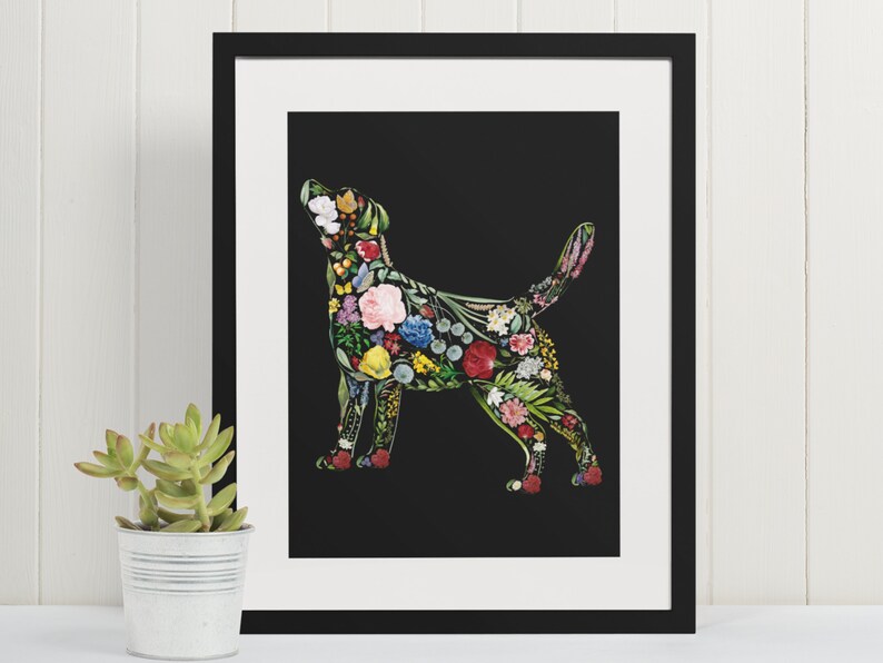 May include: A framed art print featuring a dog silhouette filled with colorful flowers and foliage against a black background. The artwork is in a black frame with a white mat, and a small succulent plant in a metal pot is in the foreground.
