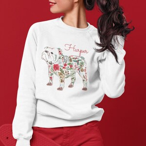 Peut inclure: Sweat-shirt blanc avec un bouledogue floral. Le bouledogue est compos&eacute; d'&eacute;l&eacute;ments floraux rouges, verts et blancs. Le nom "Harper" est &eacute;crit en script rouge au-dessus du bouledogue.