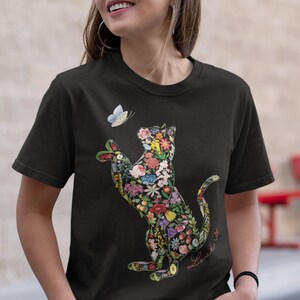 May include: Black t-shirt featuring a floral cat design with a butterfly. The cat is filled with colorful flowers and leaves. A small butterfly hovers near the cat's paw. The word "Love" is written in cursive.