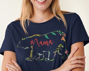 May include: Navy blue t-shirt featuring a floral bear design with the word "Mama" in red script. The bear is outlined with various flowers and leaves in shades of green, yellow, and pink. A casual, nature-themed tee.