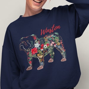 Peut inclure: Sweat-shirt bleu marine avec un bouledogue floral. Le bouledogue est orn&eacute; de fleurs et de feuillages rouges, blancs et verts. Le nom "Winston" est &eacute;crit en script rouge au-dessus du chien.