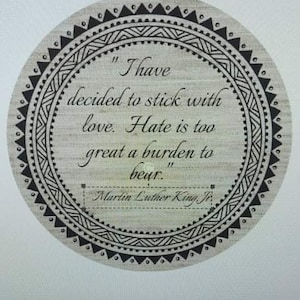 May include: A round, black and white patterned coaster with a quote by Martin Luther King Jr. that reads "I have decided to stick with love. Hate is too great a burden to bear."