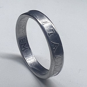 May include: A silver ring with an inscription that reads "EMIT III VITT", which is likely a Latin phrase.