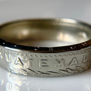 May include: A silver ring made from a Guatemalan coin. The ring features the word "GUATEMALA" engraved on the band.