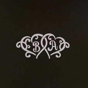 May include: A white monogram design featuring the letters "BA" in a heart shape, with the letter "B" in a separate heart shape, all intertwined with decorative flourishes.
