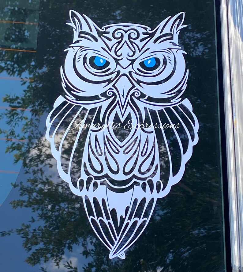 May include: White owl silhouette with intricate tribal patterns and bright blue eyes. The owl is facing forward with its wings spread out.