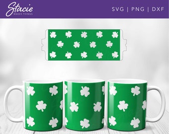 Può includere: Tre tazze bianche con sfondo verde e un motivo a trifoglio bianco. Le tazze sono su una superficie di legno.