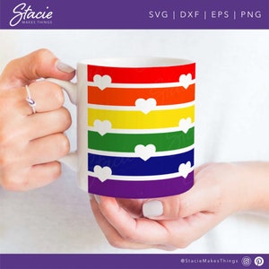 May include: White ceramic mug with a rainbow stripe design and white hearts. The rainbow stripes are red, orange, yellow, green, blue, and purple.