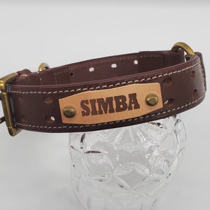 Puede incluir: Collar de perro de cuero marr&oacute;n con hebilla de lat&oacute;n y una placa de identificaci&oacute;n que dice "SIMBA".