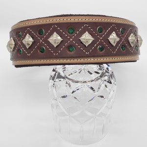May include: A brown leather dog collar with a tan trim and green and silver embellishments.