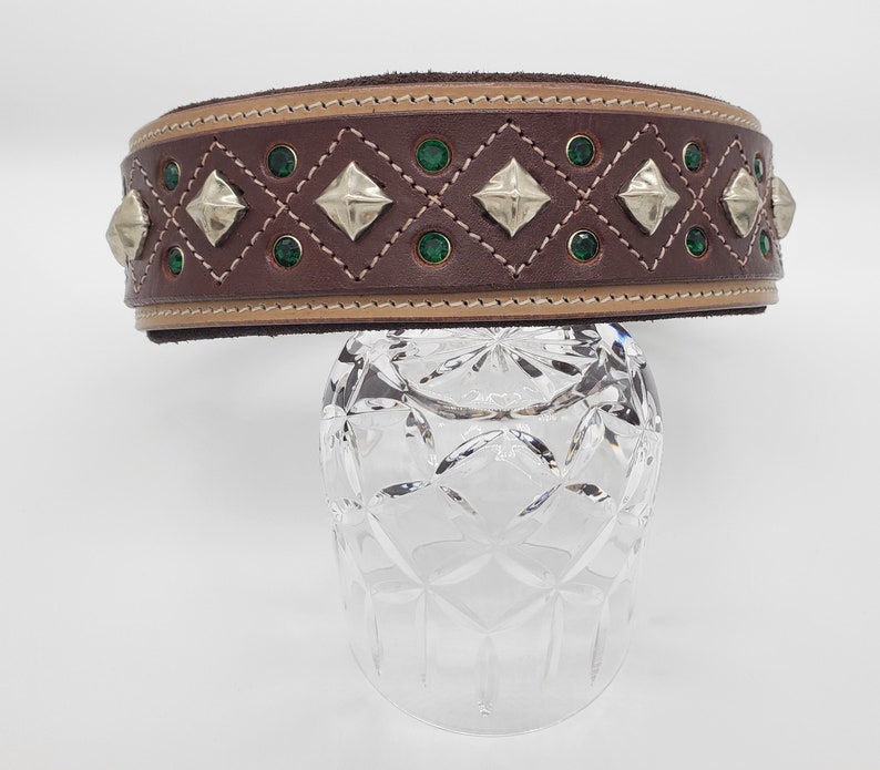 May include: A brown leather dog collar with a tan trim and green and silver embellishments.