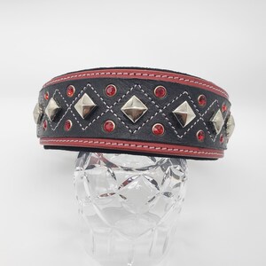 May include: Black leather dog collar with red stitching and silver pyramid studs. The collar is decorated with red rhinestones.
