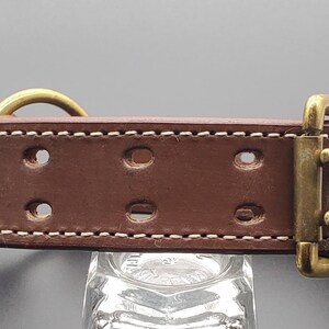 Puede incluir: Collar de perro de cuero marr&oacute;n con costuras blancas y herrajes de lat&oacute;n. El collar tiene varios agujeros para ajustar el tama&ntilde;o.