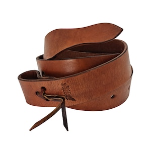 May include: A brown leather belt with a braided strap and a metal buckle. The belt has a small leather loop with the text "Lazing Days" embossed on it.