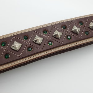 May include: Brown leather belt with a decorative design of silver pyramid studs and green rhinestones.