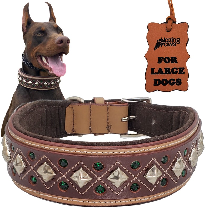 May include: Brown leather dog collar with green rhinestones and silver studs. The collar is decorated with a diamond pattern and has a tan leather lining. The collar is labeled "Blazing Paws" and "For Large Dogs".
