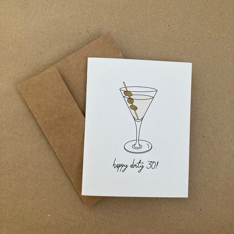 May include: A white card with a line drawing of a martini glass with olives and a stick. The text "happy dirty 30!" is written below the glass.