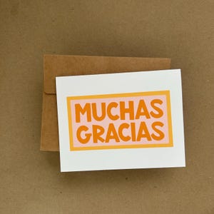 May include: A white card with a pink and orange border around the text "MUCHAS GRACIAS".