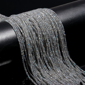 May include: A strand of small, round, iridescent white labradorite beads. The beads are strung on a thin thread and are approximately 2mm in diameter.