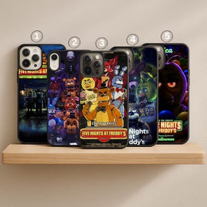 May include: Five phone cases featuring characters and text from the video game "Five Nights at Freddy's." The cases display various characters, including Freddy Fazbear, and the text "CAN YOU SURVIVE" and "FIVE NIGHTS AT FREDDY'S."