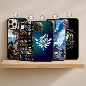 May include: Five black phone cases with various designs. The cases feature artwork with characters and logos. The cases are displayed on a wooden shelf. The designs include a landscape, icons, and a stylized emblem.