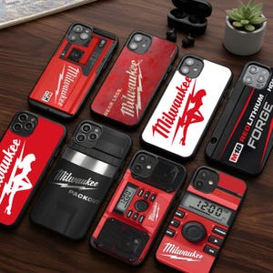 May include: A collection of phone cases featuring the Milwaukee brand logo and designs. The cases are primarily red and black, with some displaying a silhouette of a woman. Various designs include the text "WEAR LESS" and "PACKOUT".
