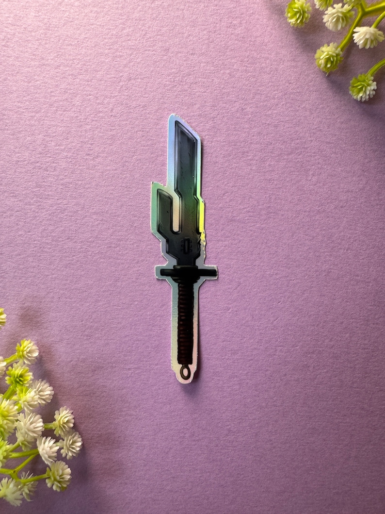 May include: A silver holographic sticker of a black sword with a brown handle.