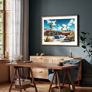 May include: A framed print of a vintage car parked in front of a mid-century modern house with palm trees and a blue sky. The house has a flat roof and a swimming pool.
