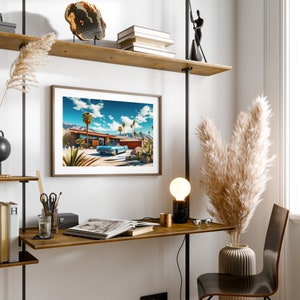 May include: A framed print of a mid-century modern home with a blue car parked in the driveway. The home is surrounded by palm trees and a blue sky with white clouds. The print is hanging on a wall with a wooden shelf above it.