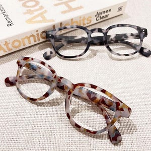 May include: Two pairs of tortoiseshell eyeglasses with clear lenses. The glasses have a round frame and a mottled pattern.