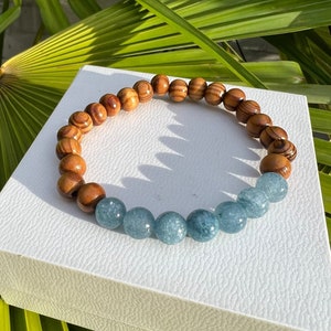 Puede incluir: Un brazalete de madera y piedras preciosas azules con cuentas de madera marrón que se alternan con cuentas de piedras preciosas azules.