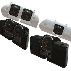 May include: A collection of four camera mounts, including two white dual-lens housings and two black single-lens mounts. Each unit features a spherical black lens with a thin gold-colored ring, set within a structured, angular mounting bracket.