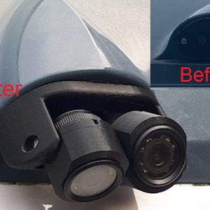 以下が含まれることがあります： 車両に取り付けられたバックカメラシステムの設置前後の画像。カメラシステムは黒色で、レンズが2つあります。カメラは車両の後部に設置されています。