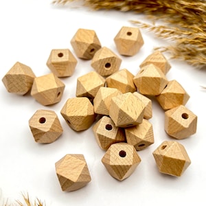 Könnte beinhalten: Eine Gruppe von Naturholzkugeln mit geometrischer, facettierter Form. Die Kugeln haben ein Loch in der Mitte zum Aufziehen.