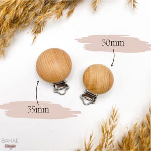 May include: Two wooden teethers with silver clips. The teether on the left is 35mm in diameter and the teether on the right is 30mm in diameter.