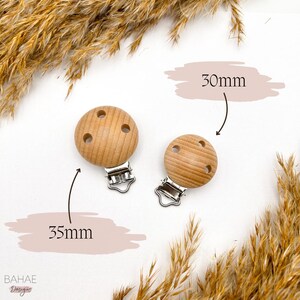 May include: Two wooden baby teether clips, one 30mm and one 35mm, with silver metal clips. The teethers are light brown and have three holes each.