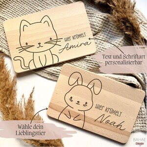 May include: Two wooden cutting boards with a cat and bunny design. The boards are personalized with the text "Hier Kr&uuml;melt" and a name. The text and font can be customized.
