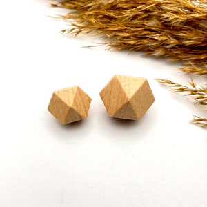 May include: Two wooden geometric shapes, one larger than the other, both in a light brown color. The shapes are similar, with multiple sides and a slightly rounded appearance.