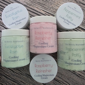 Könnte beinhalten: Fünf Tiegel der kühlenden Magnesiumcreme von The Breezy Beachwood Co. Zwei hellgrüne Tiegel sind mit Eucalyptus Rain beschriftet, zwei hellgrüne mit Peppermint Patty und ein zentraler hellrosa Tiegel mit Raspberry Refresher.