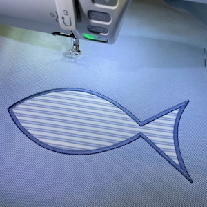 May include: A blue and white striped fish design being embroidered on a light blue fabric. The embroidery machine is visible in the top of the image.
