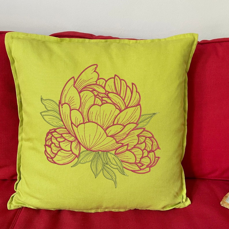 Pu&ograve; includere: Un cuscino quadrato verde lime con un grande design di peonia ricamata in rosa e verde. Il cuscino &egrave; posto su un divano rosso, creando un contrasto cromatico sorprendente. Il motivo floreale aggiunge un tocco di decorazione ispirata alla natura.