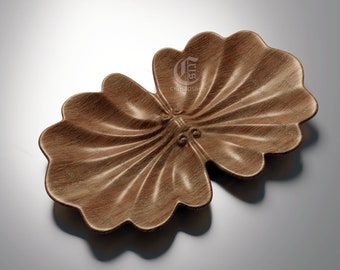 May include: A wooden decorative bowl shaped like a clam shell. The bowl is made of light brown wood and has a smooth, polished finish.