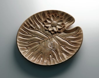 May include: A wooden decorative plate shaped like a lily pad with a carved flower in the center.
