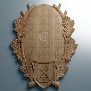 May include: A wooden plaque with a carved design of antlers, leaves, and a crossed rifle. The plaque is oval shaped and has a smooth, natural wood finish.