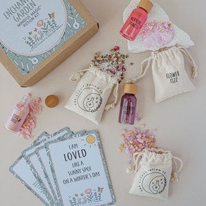 Puede incluir: Un kit de pociones m&aacute;gicas conscientes con una caja marr&oacute;n, cinco frascos peque&ntilde;os, cinco bolsitas peque&ntilde;as y cinco tarjetas de afirmaci&oacute;n. Los frascos contienen l&iacute;quidos rosas, rojos y transparentes. Las bolsitas contienen cristales rosas, blancos y transparentes. Las tarjetas tienen fondos verdes y blancos con afirmaciones impresas en ellas. La caja tiene el texto "Enchanted Garden Mindful Magic Potion Kit" impreso en ella.