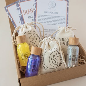 Puede incluir: Una caja de cart&oacute;n marr&oacute;n llena de un kit para hacer pociones de bruja. El kit incluye cuatro peque&ntilde;as botellas de vidrio con tapones de corcho, cada una llena de un l&iacute;quido de color diferente. Las botellas est&aacute;n etiquetadas como "Veneno de Serpiente", "Brebaje de Brujas", "Escama de Lagarto" y "Centro de la Tierra". La caja tambi&eacute;n incluye cuatro peque&ntilde;as bolsas de tela blanca con un dise&ntilde;o de luna y botella de poci&oacute;n.