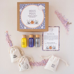 Puede incluir: Un kit de pociones m&aacute;gicas para la atenci&oacute;n plena con tres peque&ntilde;as botellas de vidrio etiquetadas como "Shake Venom", "Middle Air" y "Middle Earth". El kit tambi&eacute;n incluye cuatro peque&ntilde;as bolsas de tela blanca con las palabras "Toad Powder", "Hocus Pocus" y "Hocus Pocus" impresas en ellas. El kit est&aacute; empaquetado en una caja marr&oacute;n con un dise&ntilde;o morado y blanco y las palabras "Hocus Pocus Mindful Magic Potion Kit" impresas en ella.