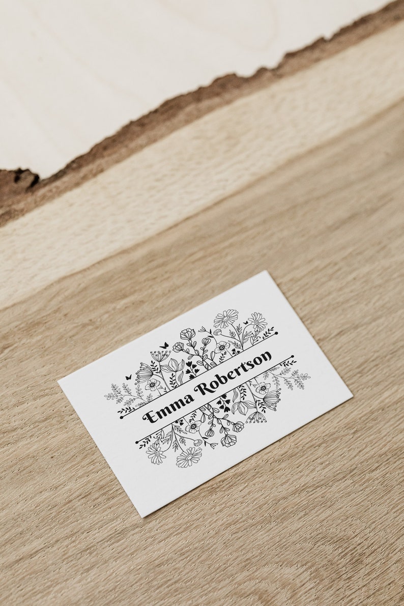 Puede incluir: Una tarjeta blanca con un dise&ntilde;o floral negro y el texto "Emma Robertson" en una pancarta.