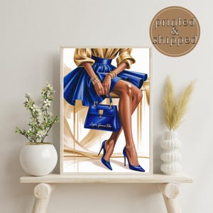 May include: A framed fashion illustration featuring a woman in a gold top and a blue skirt, holding a blue handbag. The artwork includes blue high heels and gold jewelry. The text "Sigma Gamma Rho" is visible on the handbag.