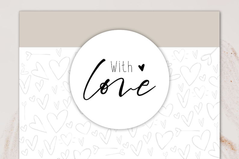 以下が含まれることがあります： 黒い筆記体で「With Love」と書かれた白い丸いステッカーと小さな黒いハート